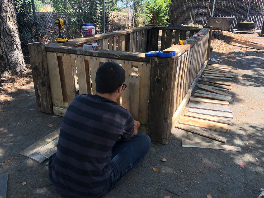 Luis Agurto III building the planter boxes from the wooden pallets